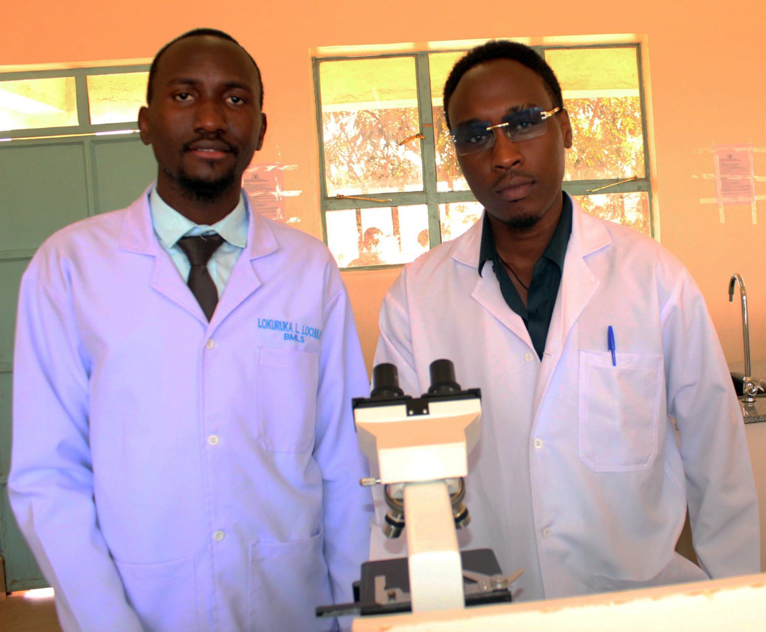 Medical laboratory sciences tutors beside a binocular microscope